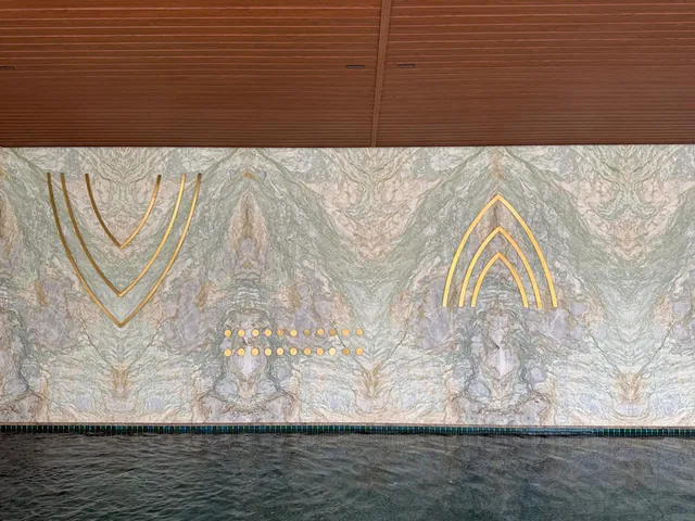 Multi-coloured book-matched stone wall beside an indoor swimming pool